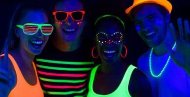 Fiesta fluor para adultos con luces UV, ropa brillante y pintura fluorescente en un ambiente vibrante.