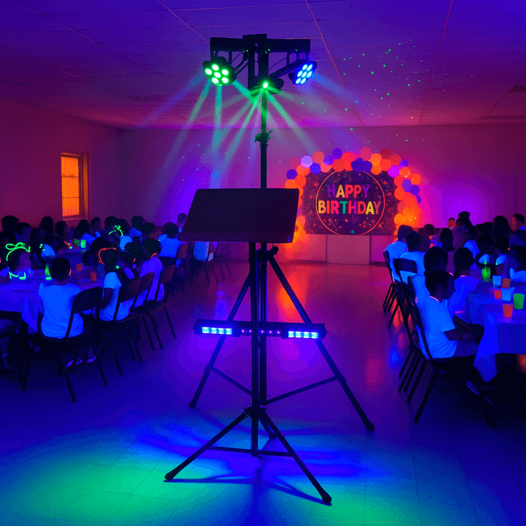 Atril con focos LED y barras UV iluminando fiesta flúor de cumpleaños infantil en una sede social.